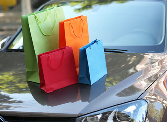 Bright shopping bags on car hood outdoors