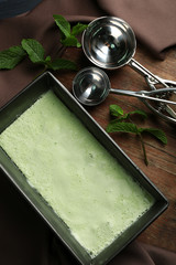 Homemade ice cream in frozen metallic container on dark wooden background
