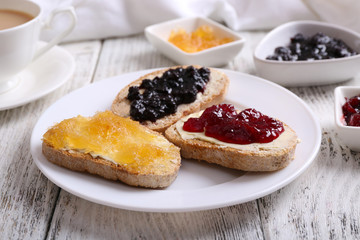 Fresh toast with butter and different jams on table close up