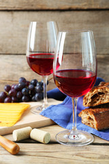 Still life of wine, grape, cheese and bread on rustic wooden background