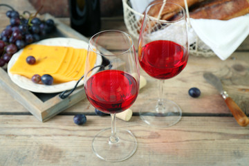Still life of wine, grape, cheese and bread on rustic wooden background