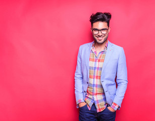 Smiling young fashion man holding his hands in pockets