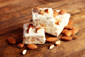 Sweet nougat with almonds on wooden background