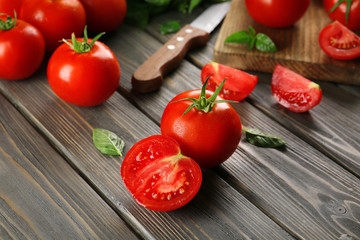 Red tomatoes and knife on wooden background