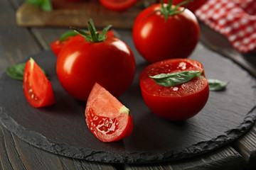 Red tomatoes and round cutting board on wooden background