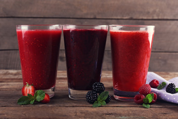 Three glasses of berry cocktails on wooden background