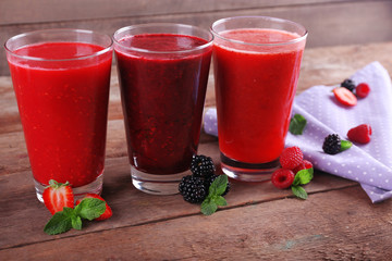 Three glasses of berry cocktails on wooden background