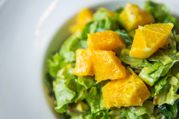 A fresh green salad with oranges served on a white plate in a restaurant in Tirana, Albania.
