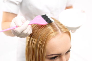 Obraz premium Koloryzacja włosów w salonie fryzjerskim.Fryzjer nakłada farbę do włosów za pomocą pędzelka