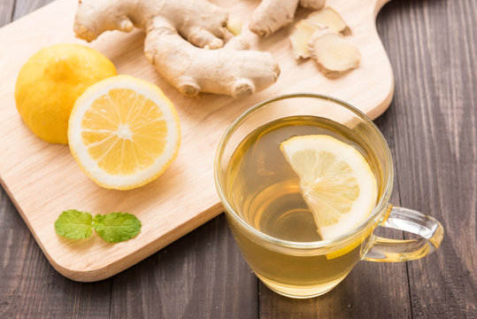Cup of ginger tea with lemon on wooden background