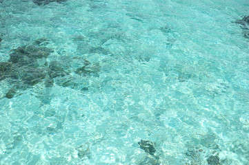 Clean blue water texture, with ripples and sun reflections, at summer in Maldives.