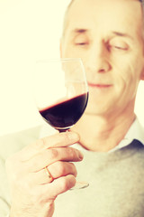 Mature man tasting red wine