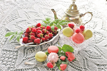 Macaroons with raspberries on metal plate for breakfast on lace