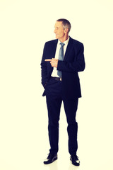 Full length businessman pointing to the left