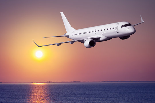 Passenger airplane flying on sunset