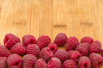 Ripe sweet raspberries on wood table close-up