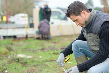 Builder taking measurements in the garden