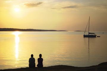 Naklejka na ściany i meble backlit couple admiring the sunrise over the sea