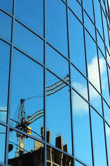 reflection of the sky in the glass windows of the crane construction