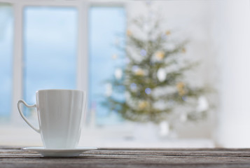 white cup on background Christmas fir and window