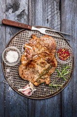 roast pork with garlic, salt and red sauce on iron pan c fork on wooden rustic background, top view