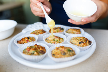 Hand of woman smears honey on cupcakes