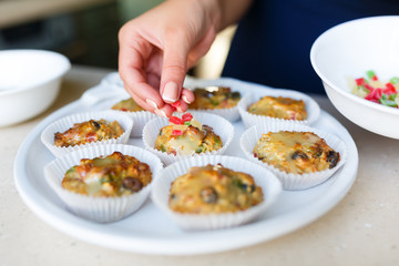 Young woman puts candied fruits on the cakes