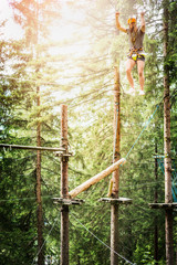 Young guy is climbing on the rope in climbing forest on nature bakgrund