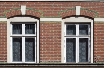 Twin windows. Fancy brickwork and alternating colours take ordinary functional windows on to a more decorative level. Simple floral net curtains complete the design.