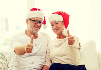 happy senior couple in santa helper hats at home