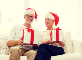 happy senior couple in santa hats with gift boxes