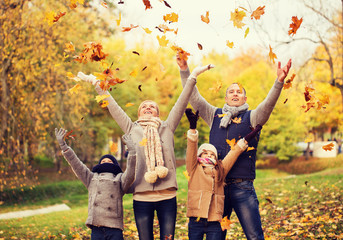 happy family playing with autumn leaves in park
