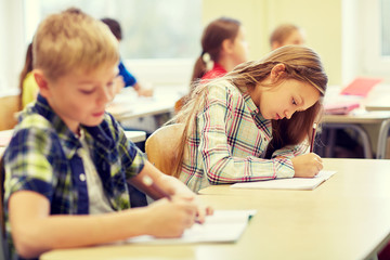 group of school kids writing test in classroom