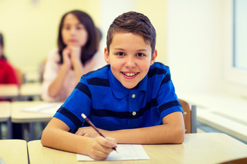 group of school kids writing test in classroom
