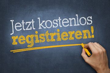 Hand schreibt mit Kreide Text "Jetzt kostenlos registrieren!" auf Tafel