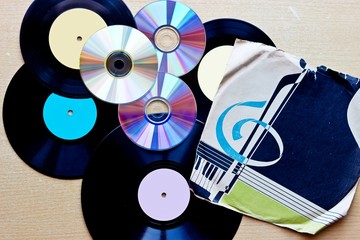 Vinyl record discs ans CD on wooden background. Top view