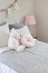 kid's bedroom with pillows and dolls on bed