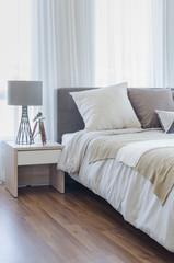 pillows on modern bed with grey lamp on wooden table side