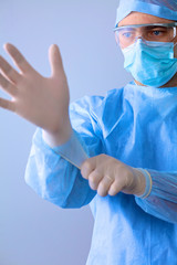 Male doctor putting on disposable gloves