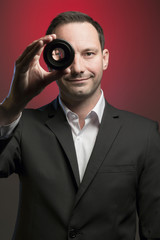 Photographer looking through lens in front of red background