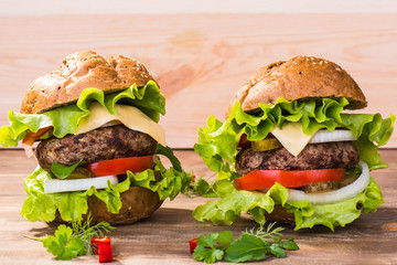 Big hamburger with beef cutlet and vegetables on wood plate
