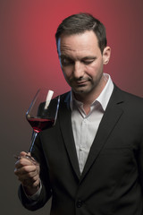 man tasting red wine in jacket in front of red background