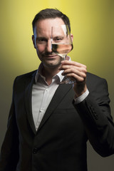 man tasting white wine in jacket in front of yellow background