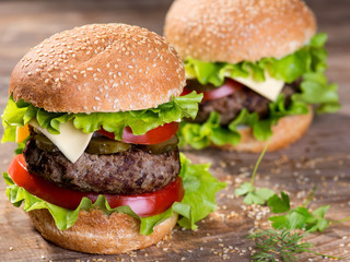 Big hamburger with beef cutlet and vegetables on wood plate
