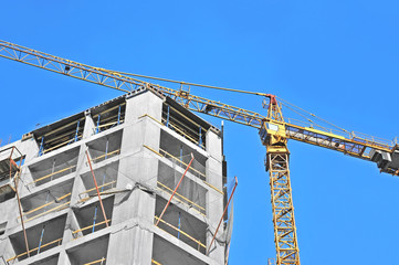 Crane and building construction site against blue sky