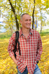 Happy man with backpack in the autumn park.