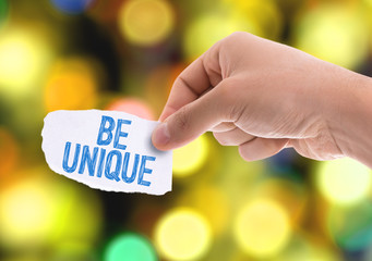 Piece of paper with the word Be Unique with bokeh background