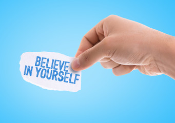 Piece of paper with the word Believe in Yourself with blue background