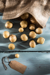 new potatoes coming out of a burlap bag, on wooden background