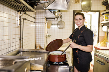 Young woman working in old kitchen smiling and cooking